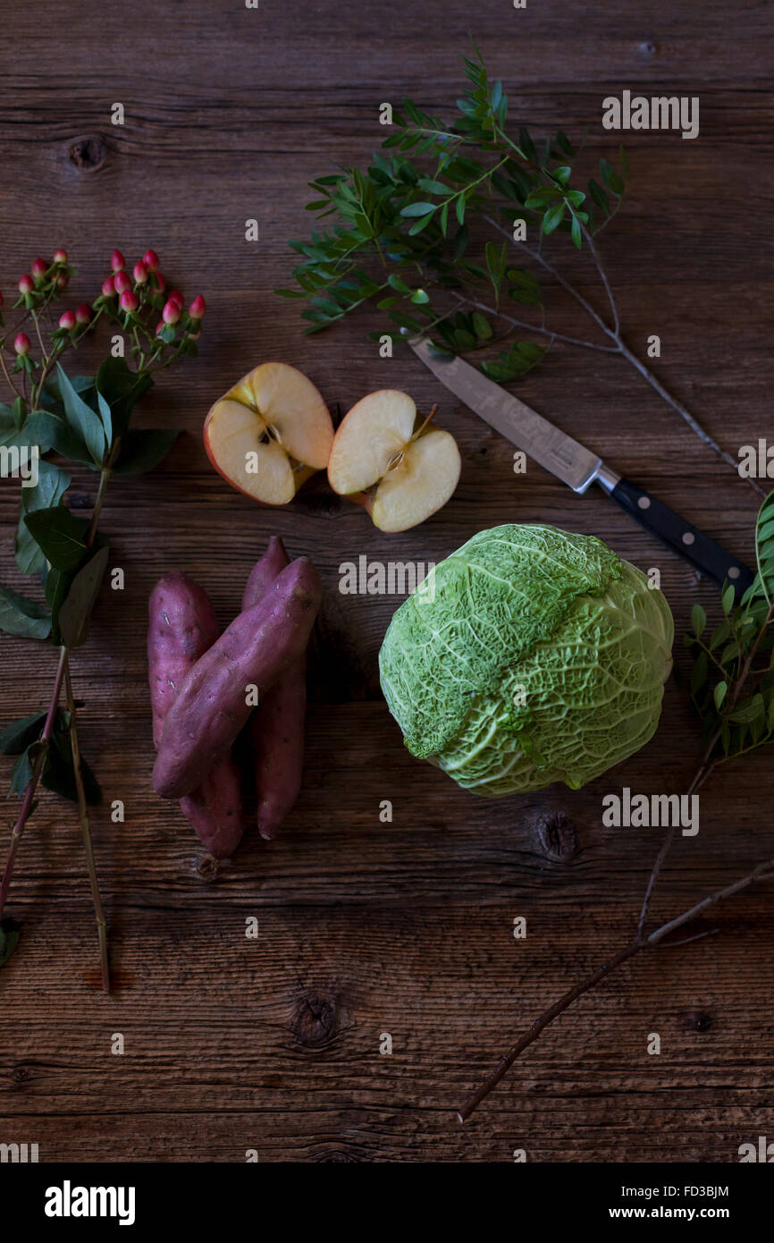 Wirsing, Apfel und Süßkartoffeln als Zutaten für einen gesunden Salat auf einem rustikalen Holztisch Stockfoto