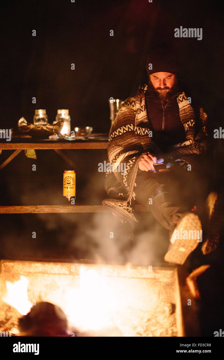 Ein Mann sitzt am Lagerfeuer in der Nacht in Big Sur, Kalifornien. Stockfoto