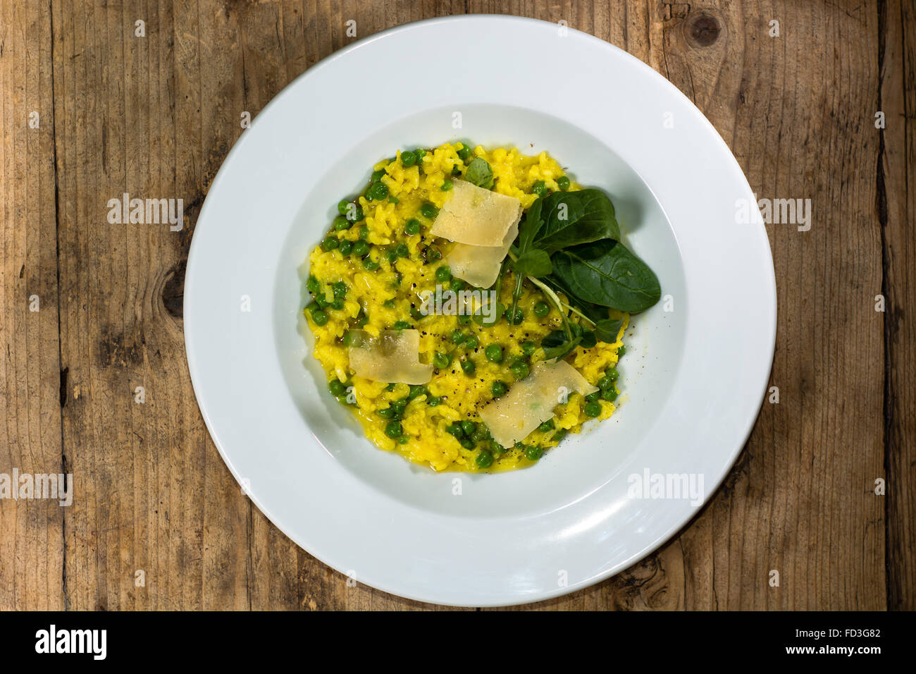 Lauch, Garten Erbsen und Safran-Risotto auf Teller. Französisches Restaurant, die Küche mit hellen gelben Reis Stockfoto