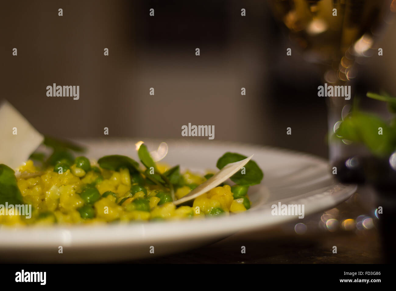 Lauch, Garten Erbsen und Safranrisotto halbe Platte mit Wein. Französisches Restaurant, die Küche mit hellen gelben Reis Stockfoto