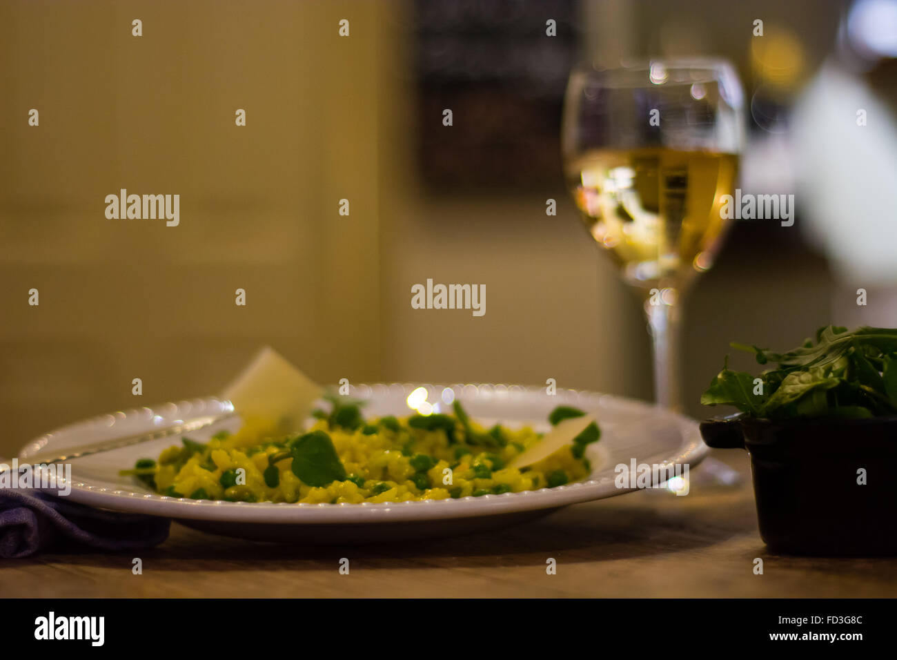 Lauch, Garten Erbsen und Safran-Risotto Teller mit Wein. Französisches Restaurant, die Küche mit hellen gelben Reis Stockfoto