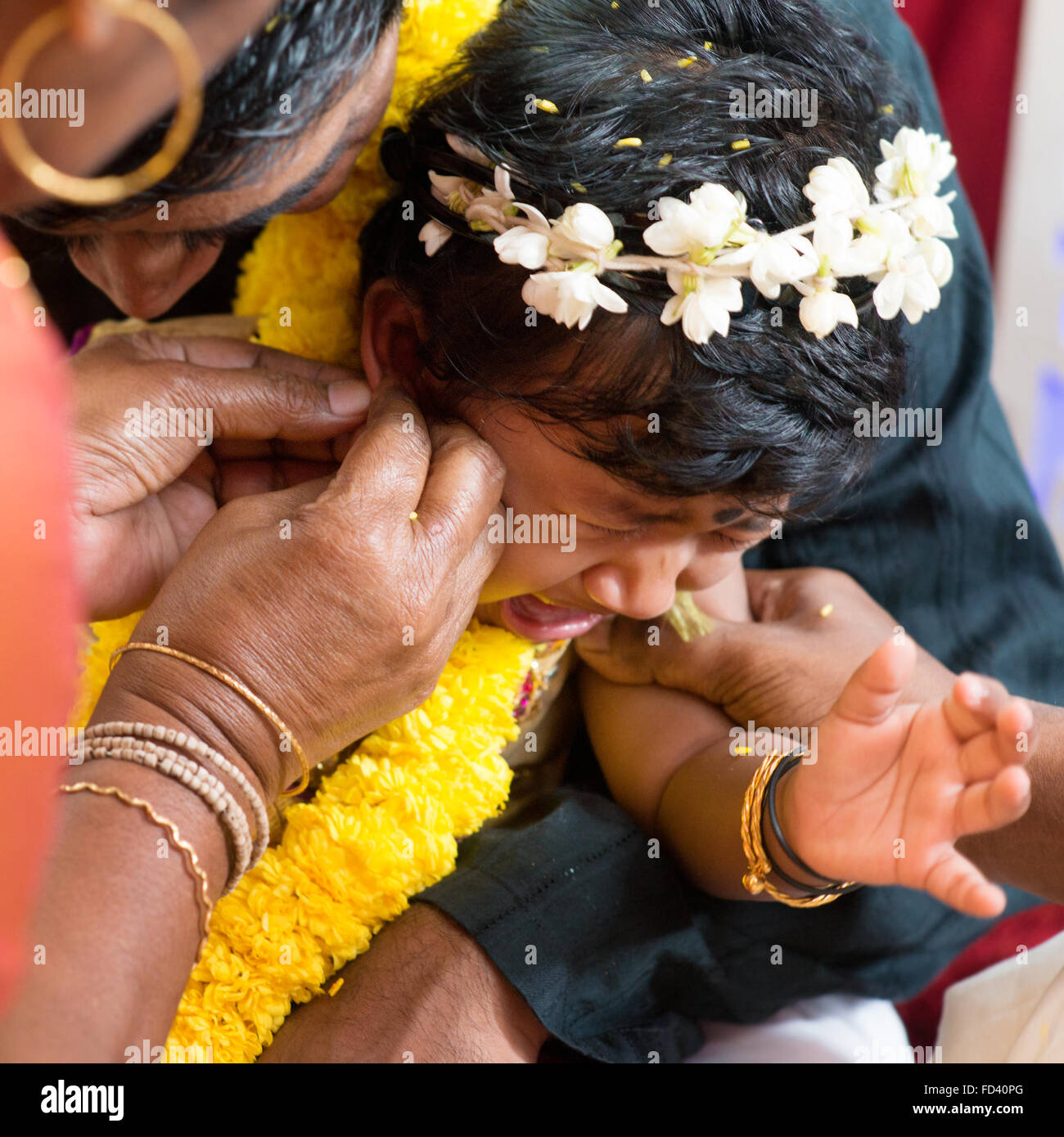 Babymädchen weint während der Karnavedha-Ereignisse. Traditionelle indische Hindus Ohrlochstechen Zeremonie. Indien spezielle Rituale. Stockfoto
