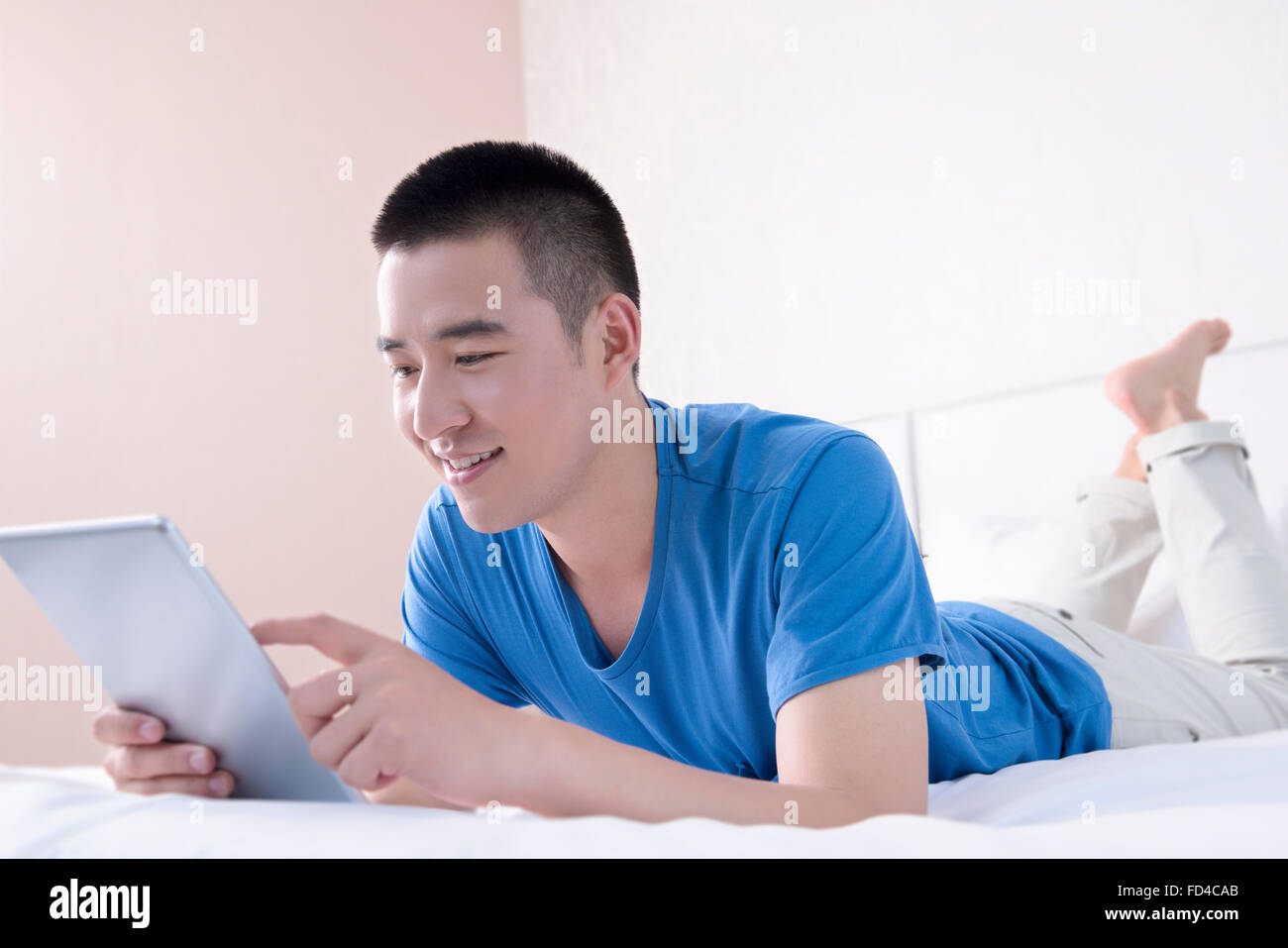 Junger Mann mit digital-Tablette im Bett Stockfoto