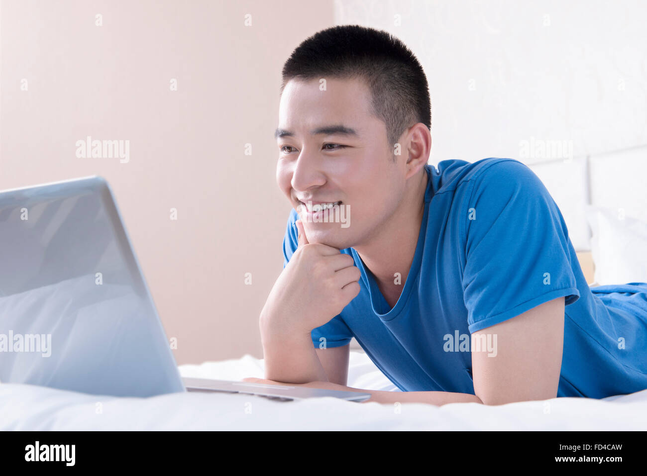 Junger Mann mit Laptop im Bett Stockfoto