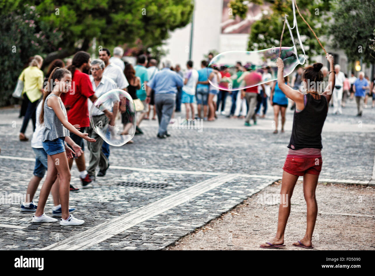 Kleine Kinder spielen mit riesige Seifenblasen in den Straßen von Athen, Griechenland Stockfoto