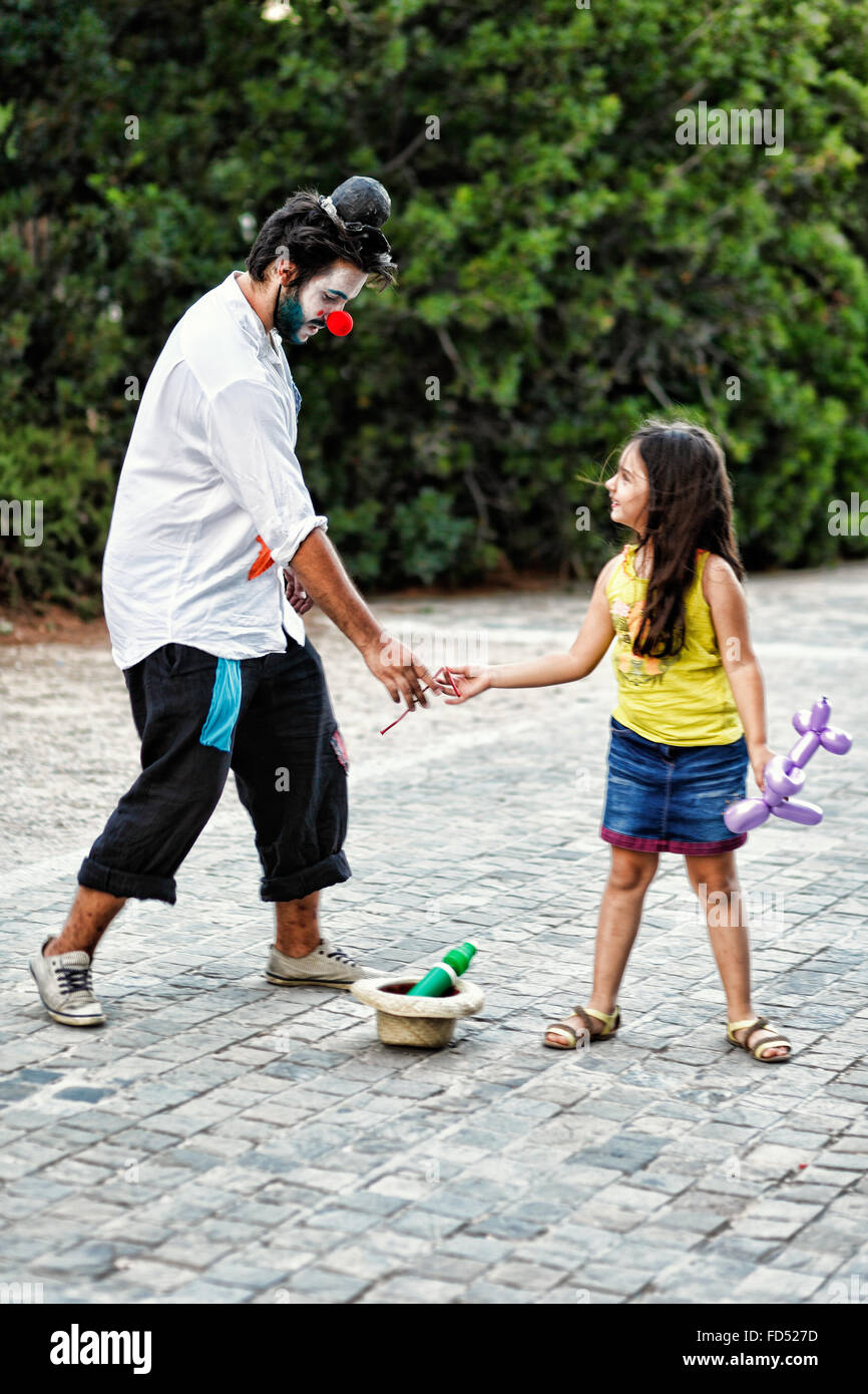 Ein Clown verleiht Ballon ein kleines Mädchen in den Straßen von Athen, Griechenland Stockfoto