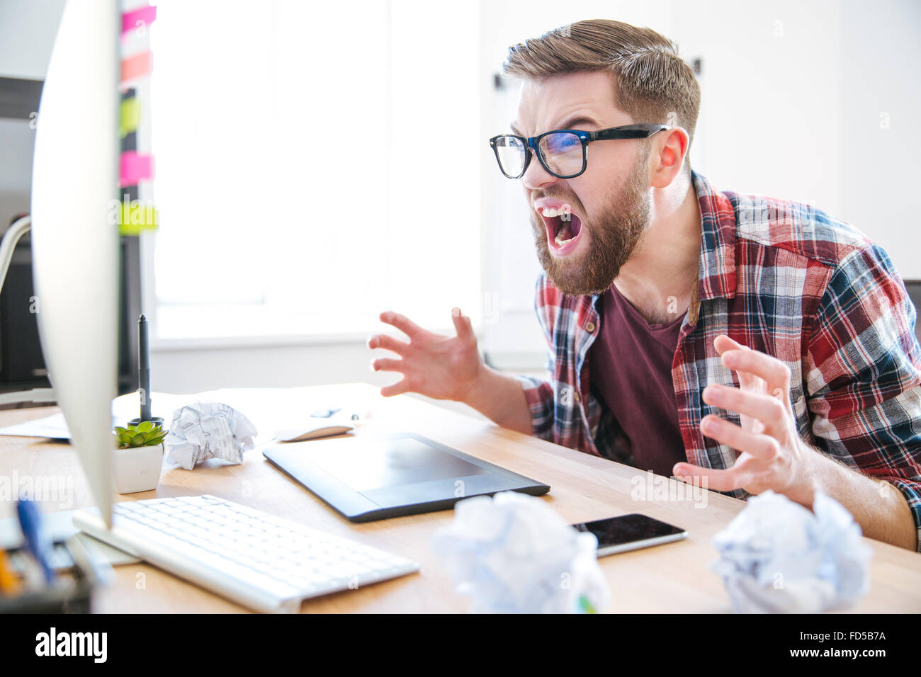 Wütender aggressiven bärtigen Mann Designer suchen am Monitor des Computers und schreien Stockfoto