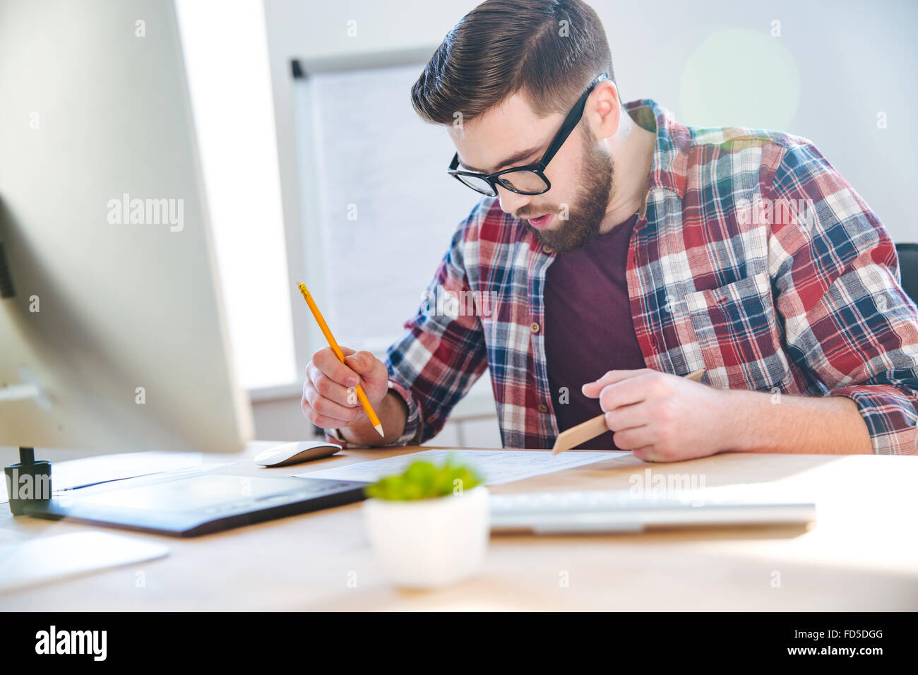 Handsome konzentriert jungen Mann mit Bart mit Bauplan mit Lineal und Bleistift im Büro arbeiten Stockfoto