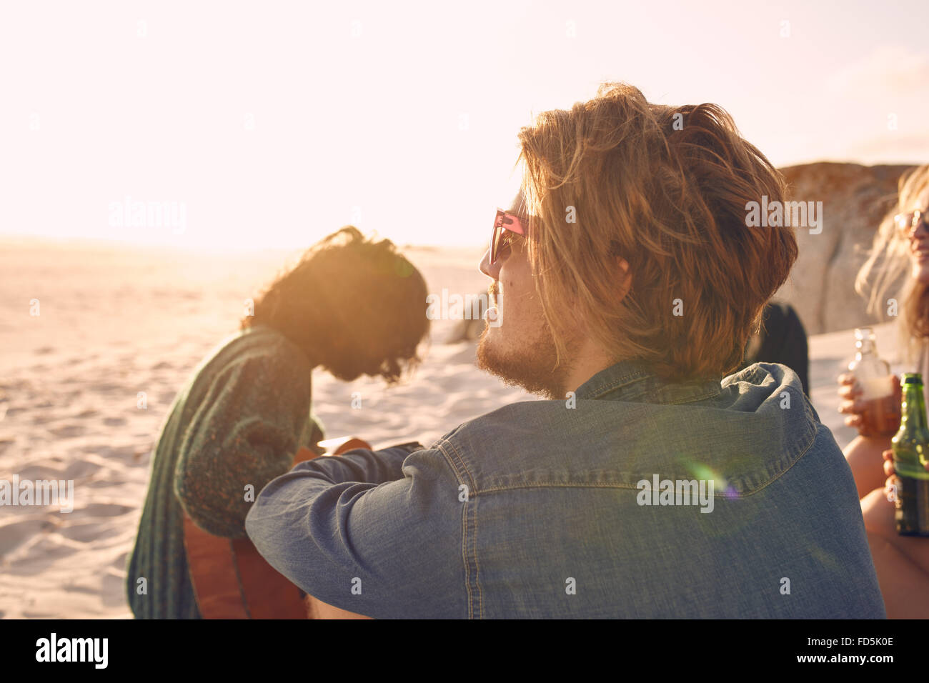 Junger Mann genießen einen Sommertag am Strand mit Freunden im Hintergrund. Junge Menschen, die einen Tag am Strand zu genießen. Stockfoto