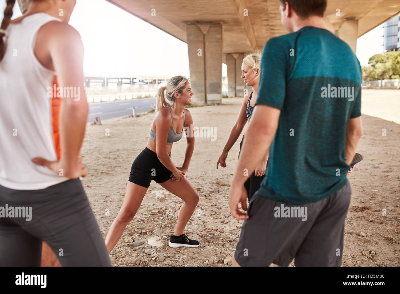 Passen Sie junge Frau mit fließendem Club-Gruppe nach einem Lauf dehnen. Junge Leute gehen stretching Workout nach einem Morgen laufen unter Stockfoto