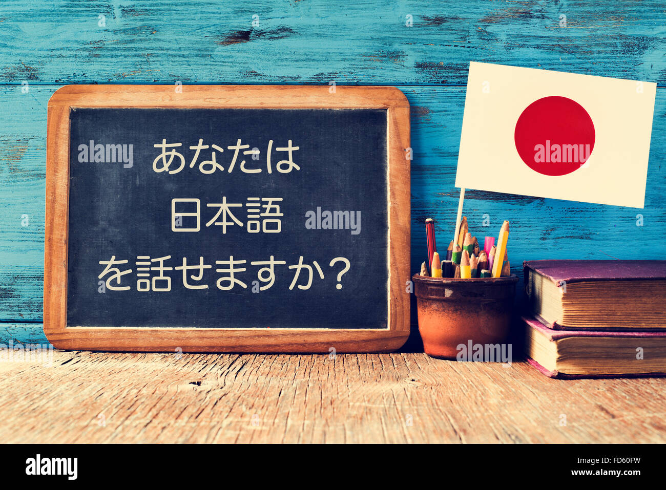 eine Tafel mit der Frage sprechen Sie Japanisch? geschrieben in Japanisch, einen Topf mit Bleistiften, einige Bücher und die Flagge von Japan Stockfoto