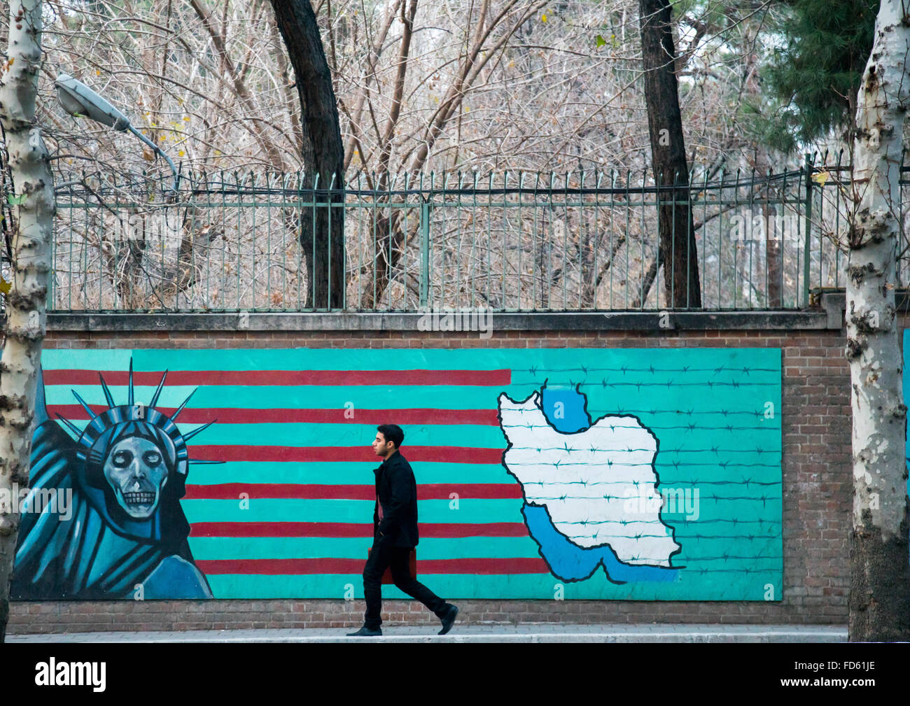 Mann vorbei Wandbild Anti-amerikanische Propaganda Slogan zeigen Statue Freiheit Skelett an der Wand des ehemaligen US-Botschaft, Central District, Teheran, Iran Stockfoto