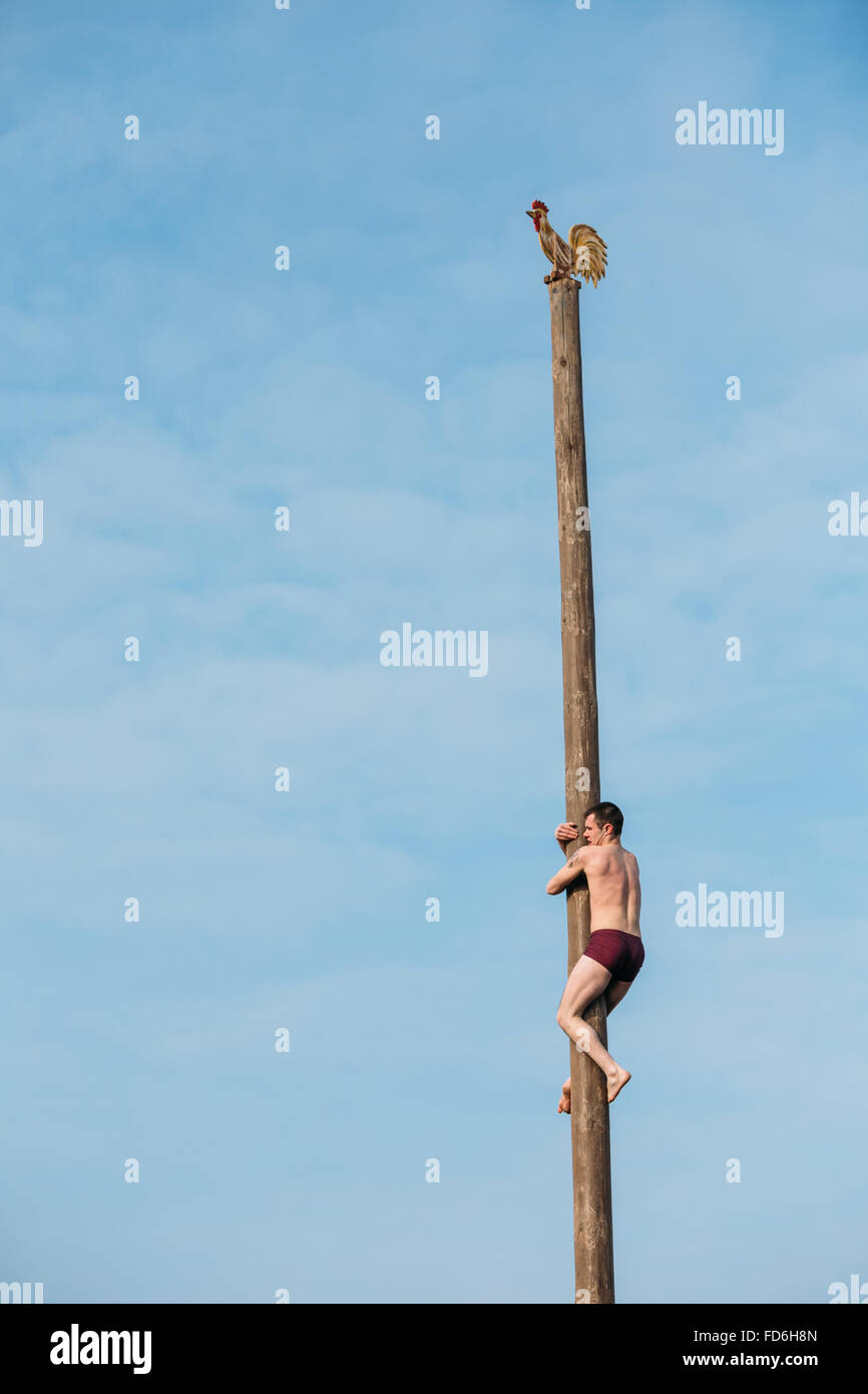 Slawische feiern Fasching. Mann klettert auf hölzernen Pfosten auf traditionellen Urlaub im Zeichen des Ansatzes des Frühlings Stockfoto