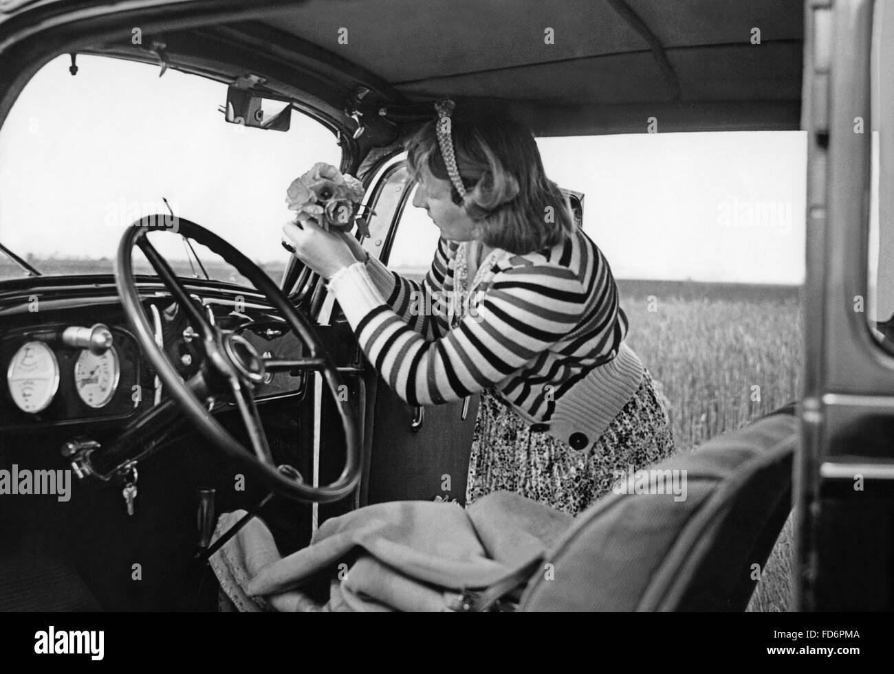 Frau, setzen einen Blumenstrauß auf dem Armaturenbrett ihres Autos, 1939 Stockfoto