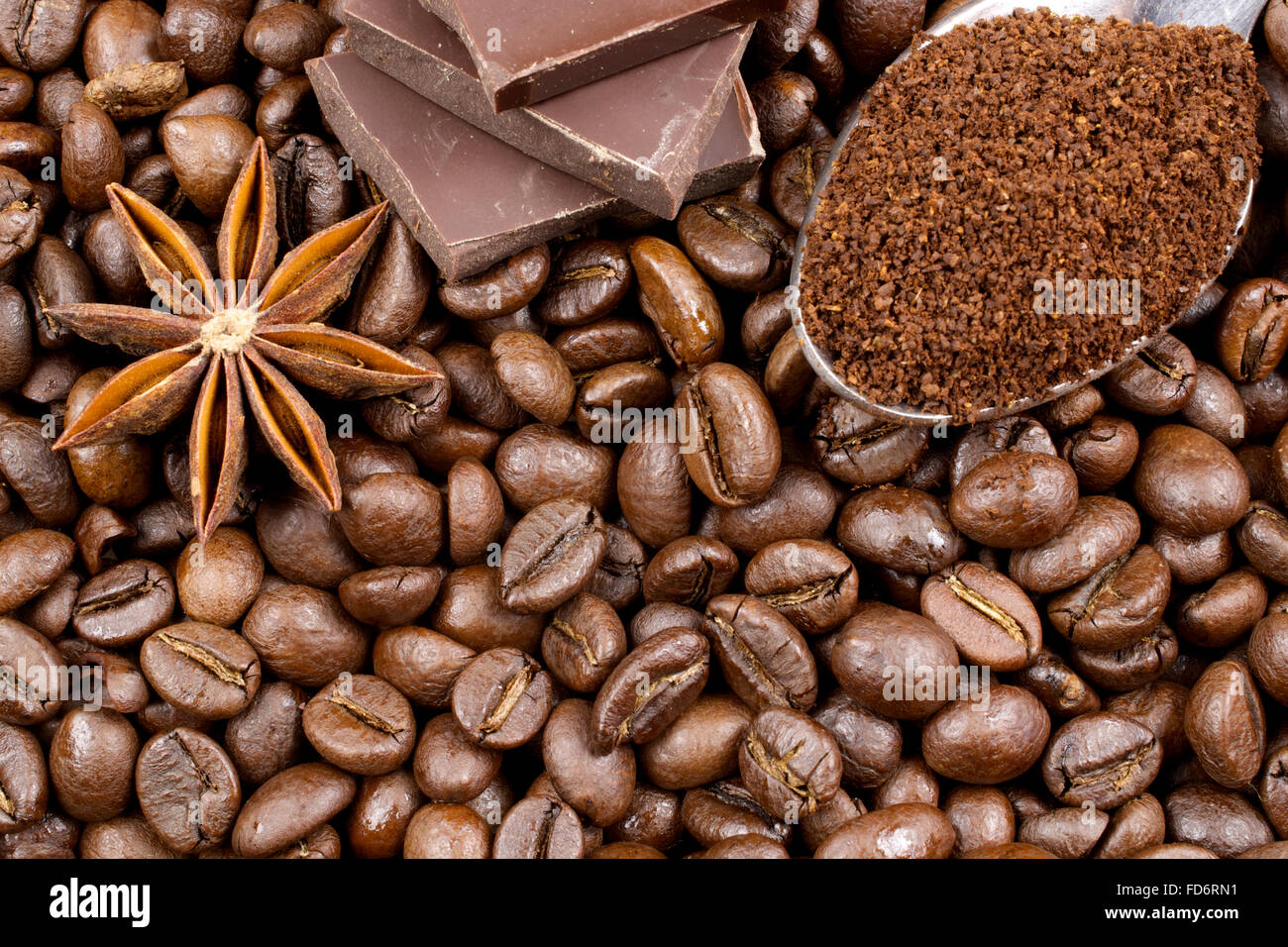 Gemahlenen Kaffee in den Löffel, Schokolade und Anis auf Kaffeebohnen Hintergrund Stockfoto