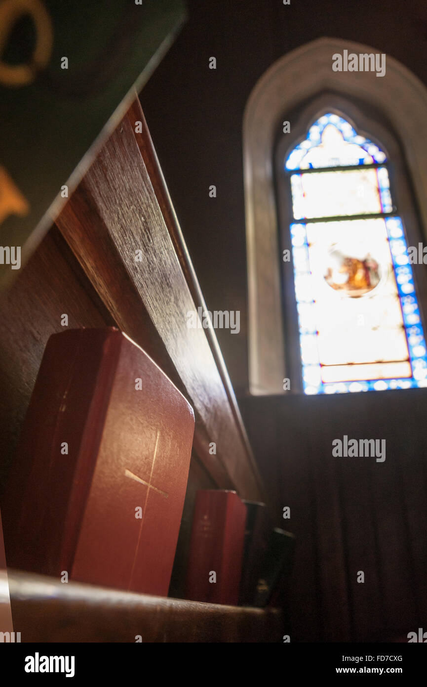 Christliche Bibel in Kirchenbänken mit Glasfenster Stockfoto