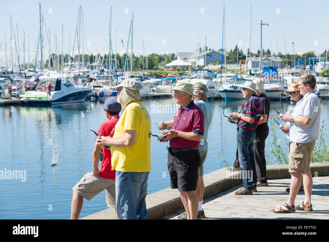 Gruppe von älteren Männern racing mit remote gesteuerten kleine Segelboote an einem hellen Sommertag in einer Marina. Stockfoto