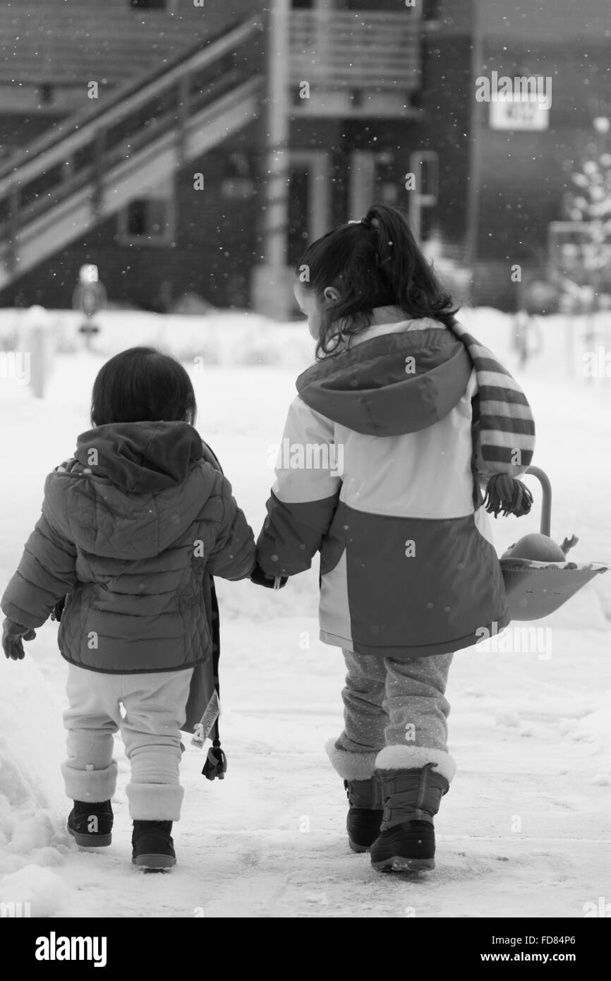 zwei junge Mädchen Hand in Hand Wandern im Schnee Stockfoto