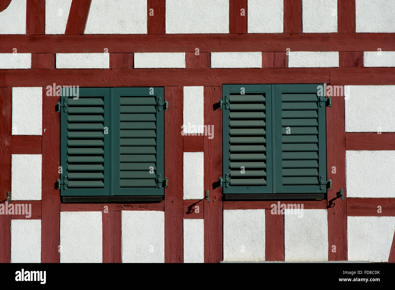 Gerahmte Holzwand mit zwei Fenstern mit geschlossenen Fensterläden Stockfoto