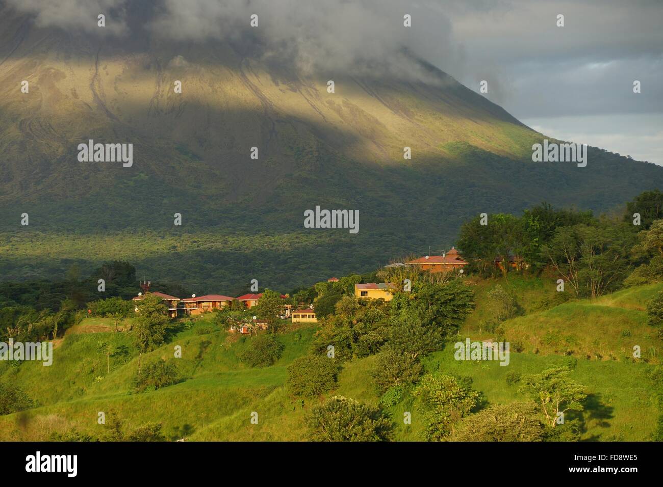 Siedlung an der Unterseite des Vulkans Arenal, Costa Rica mit Vulkan im Hintergrund. Stockfoto