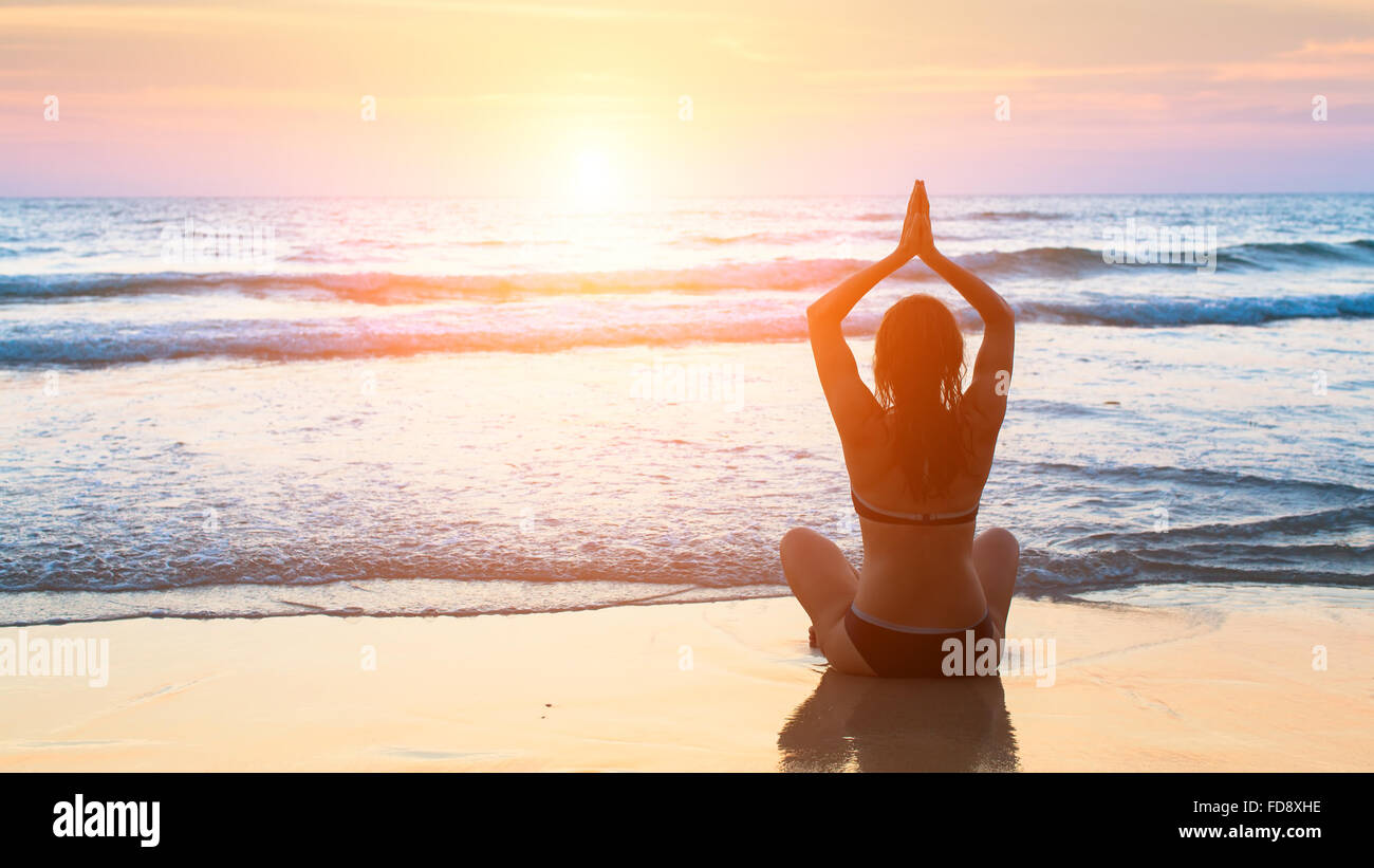 Silhouette-Meditation-Yoga-Frau im Hintergrund auf das Meer und die herrlichen Sonnenuntergänge. Yoga-Silhouette. Stockfoto