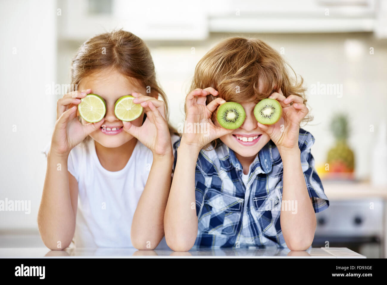 Zwei Kinder in der Küche versteckt ihre Augen hinter Früchte Stockfoto
