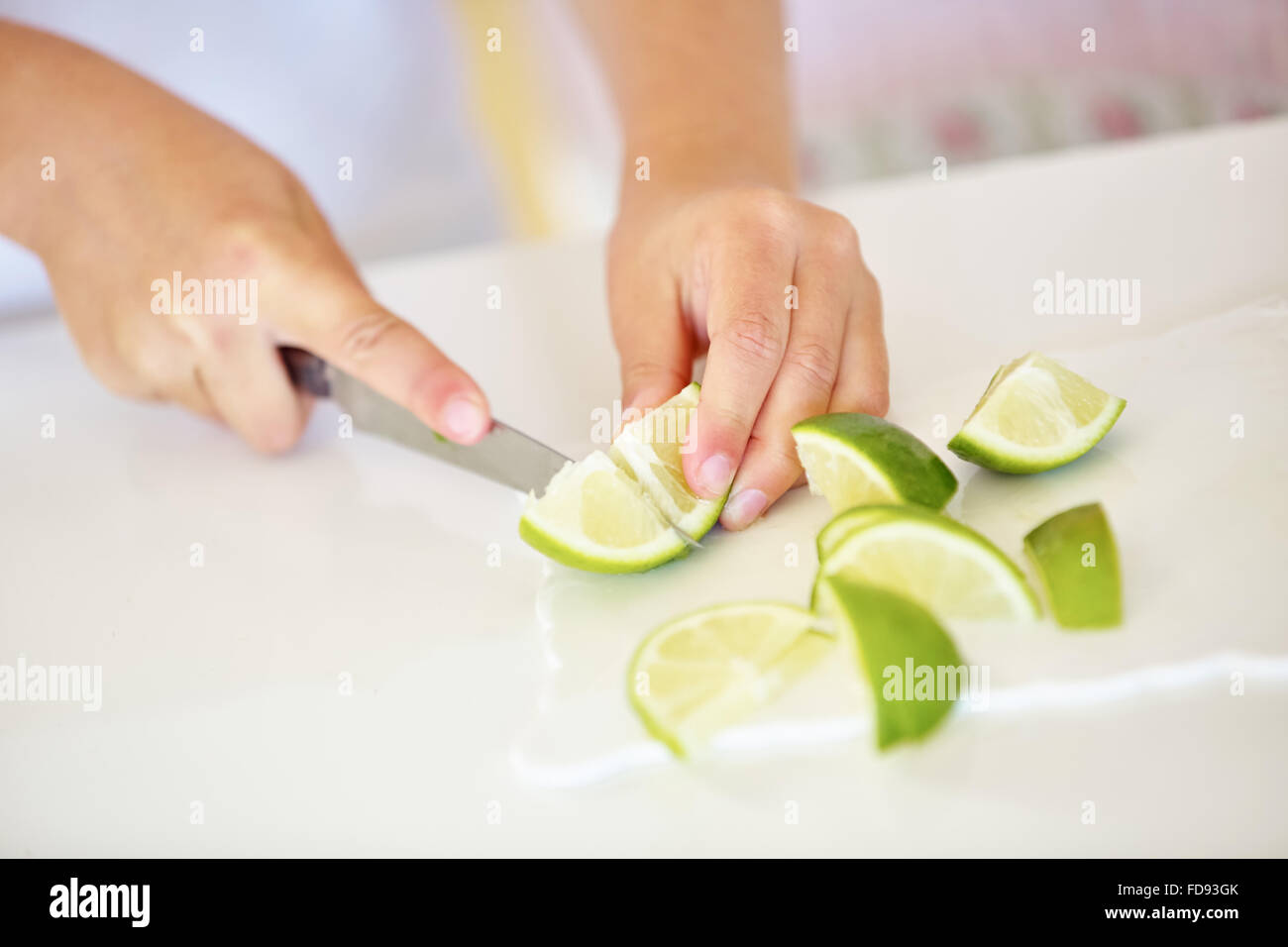 Hände, frische Limette Früchte in Stücke schneiden, mit einem Messer Stockfoto