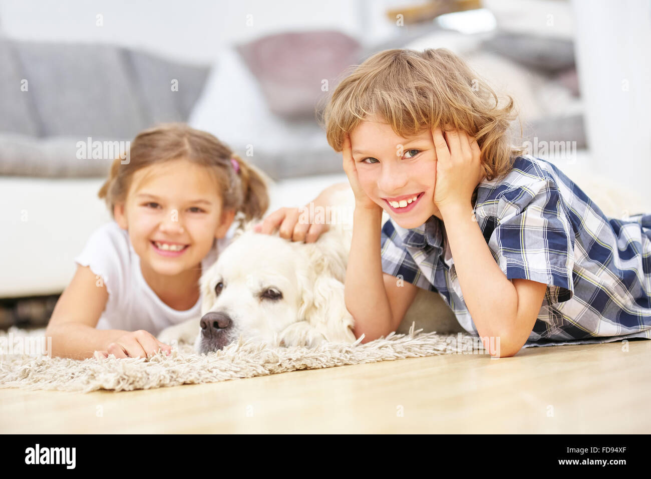 Jungen und Mädchen spielen mit Golden Retriever Hund zu Hause Stockfoto