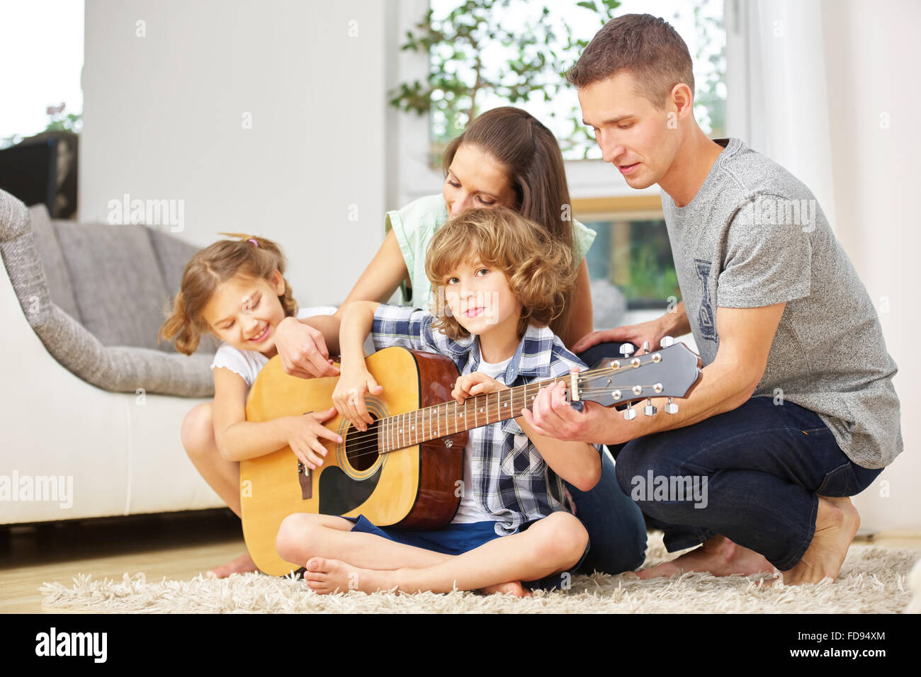 Glückliche Familie gemeinsam Musik zu machen mit Gitarre zu Hause Stockfoto