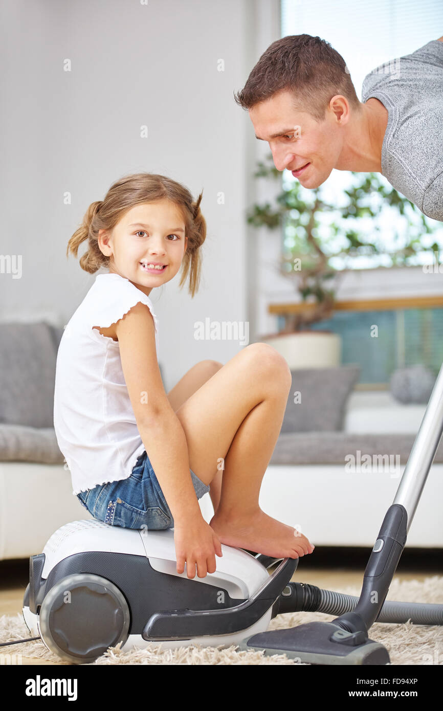 Mädchen spielen auf Staubsauger, während Vater zu Hause Reinigung ist Stockfoto