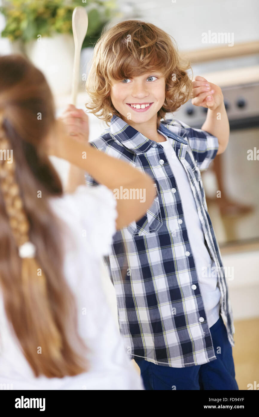 Jungen und Mädchen kämpfen in Scherz mit Holzlöffel in einer Küche Stockfoto