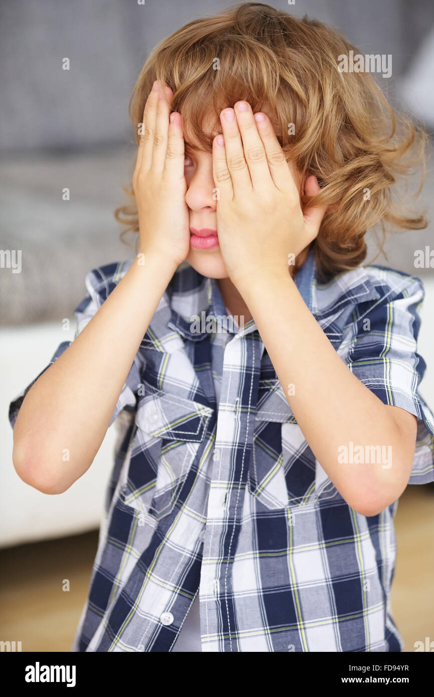 Junge, spielen verstecken und suchen und halten die Hände über die Augen zu Hause Stockfoto