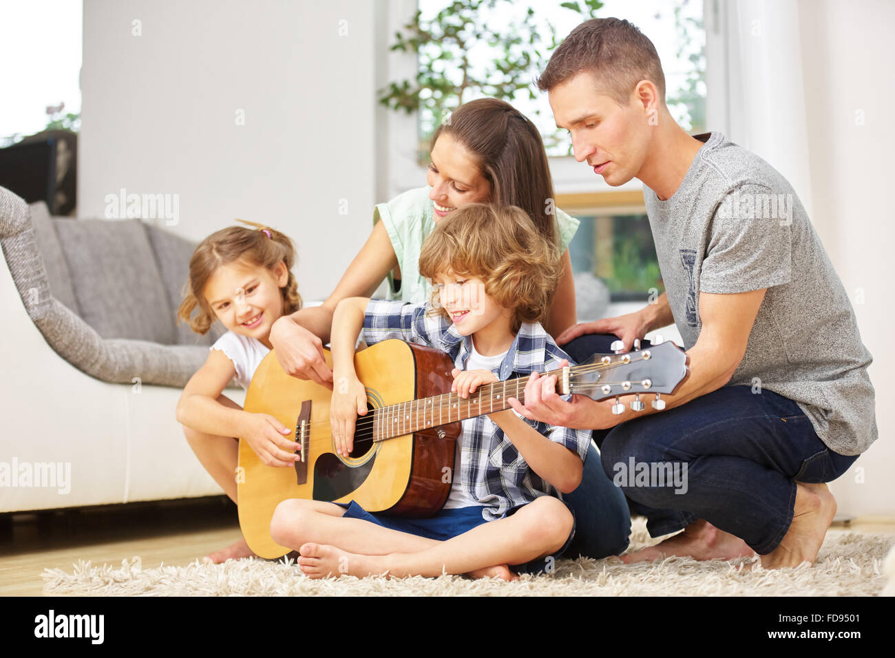 Familie Musizieren mit Gitarre zu Hause im Wohnzimmer Stockfoto