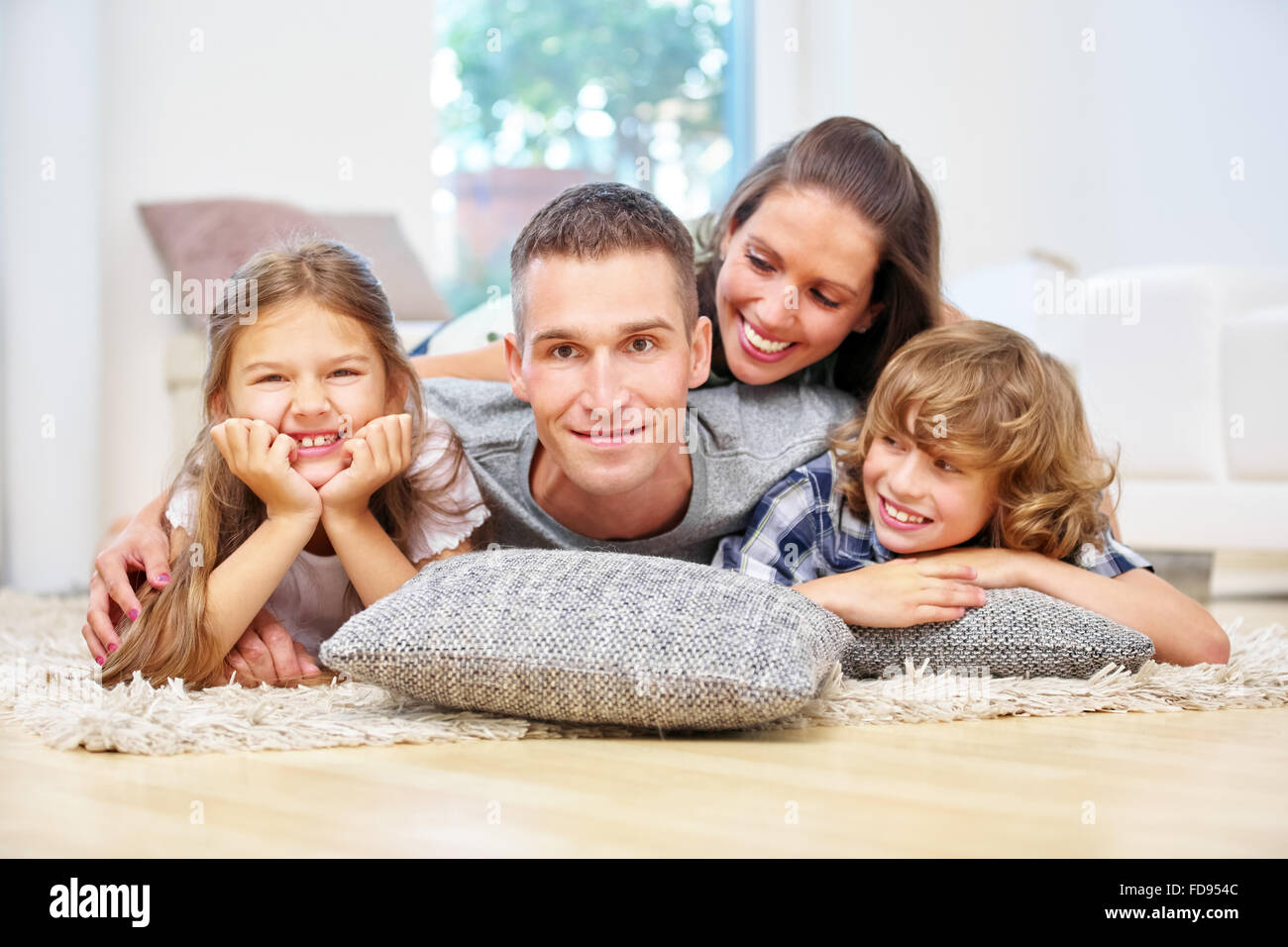 Glückliche Familie mit zwei Kindern zu Hause im Wohnzimmer Stockfoto