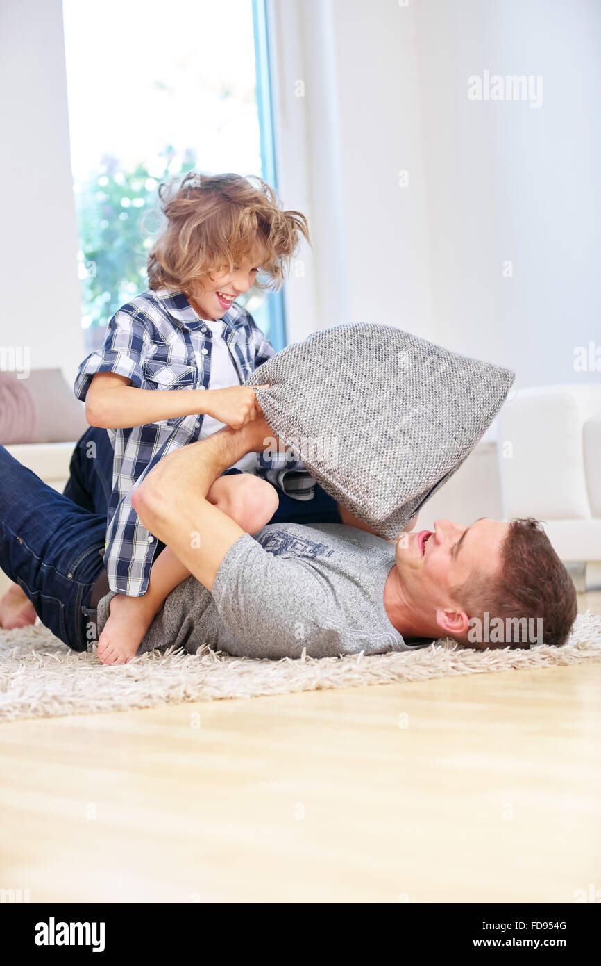Glücklicher Vater und Sohn machen Kissenschlacht zu Hause im Wohnzimmer Stockfoto