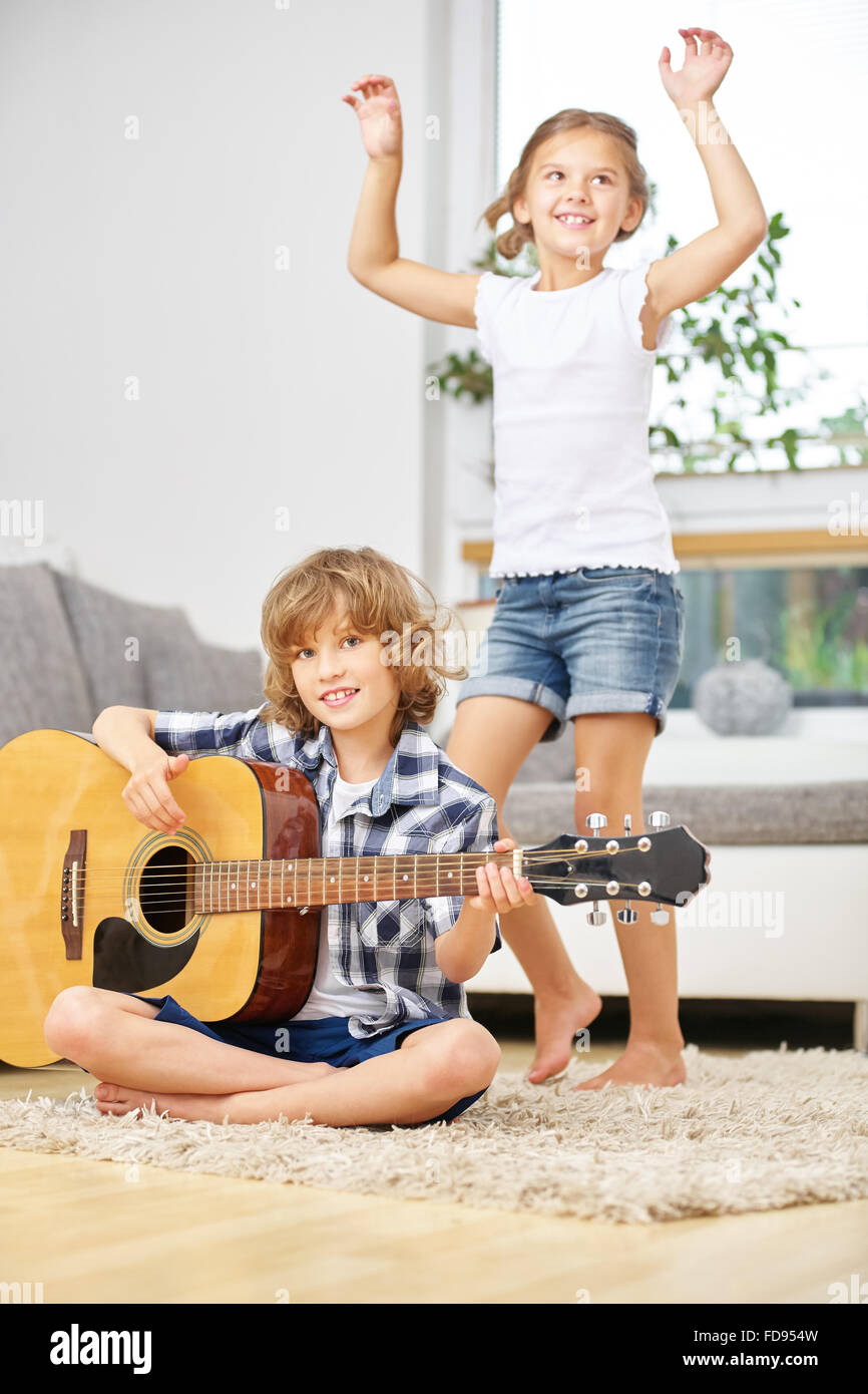 Mädchen tanzen zur Musik von jungen zu Hause Gitarre spielen Stockfoto