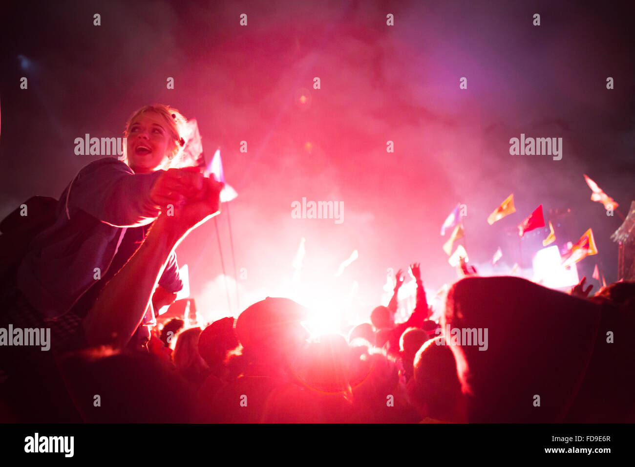 Party-Girl sitzt auf den Schultern auf einem Musikfestival. Hintergrundbeleuchtung mit Feuerwerk Stockfoto