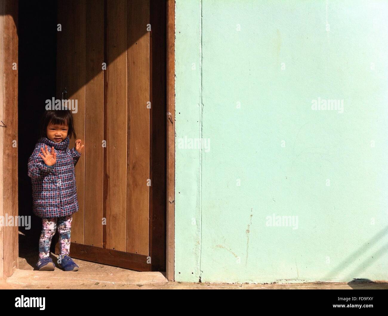 Mädchen stehen an der Tür und winkte Hand Stockfoto