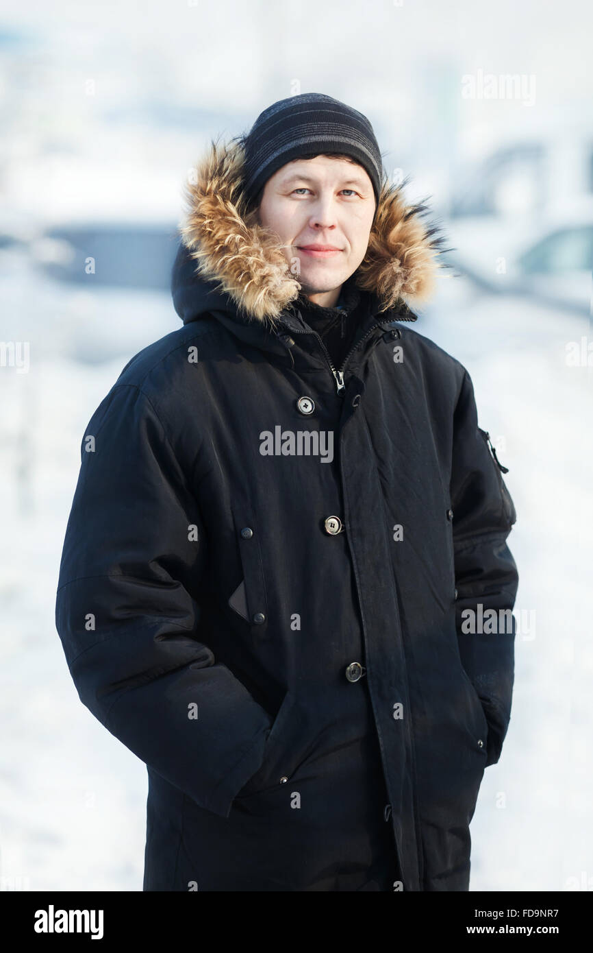 Porträt eines jungen sibirischen in kalten Wintertag, warme Daunenjacke mit Fell Kapuze, vertikale tragen. Schnee, Frost. Blick in die Kamera. Stockfoto