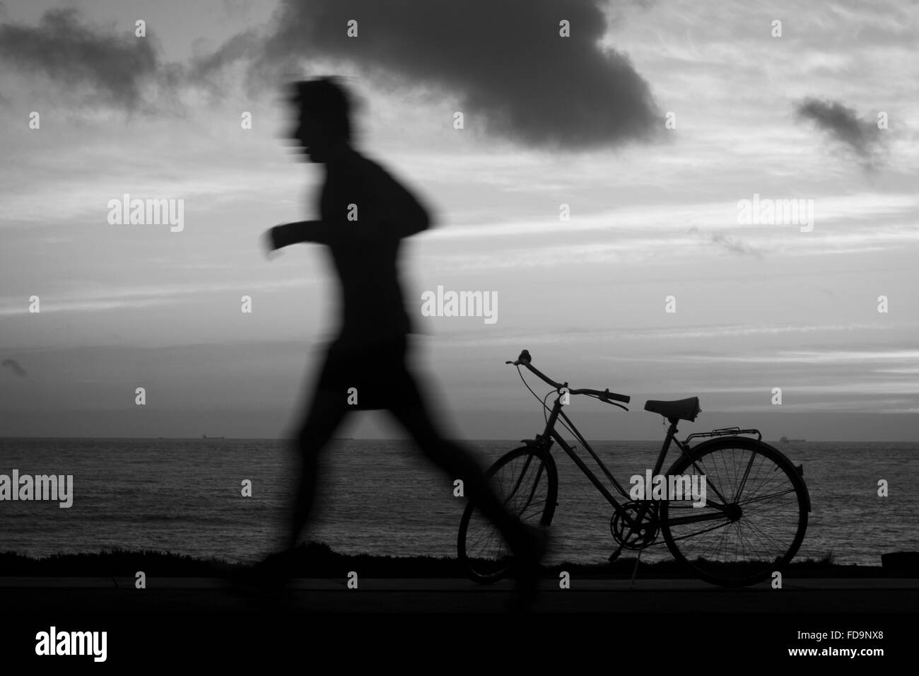 Mann läuft vorbei in der Nähe von Fahrrad, an der Strandseite. Stockfoto