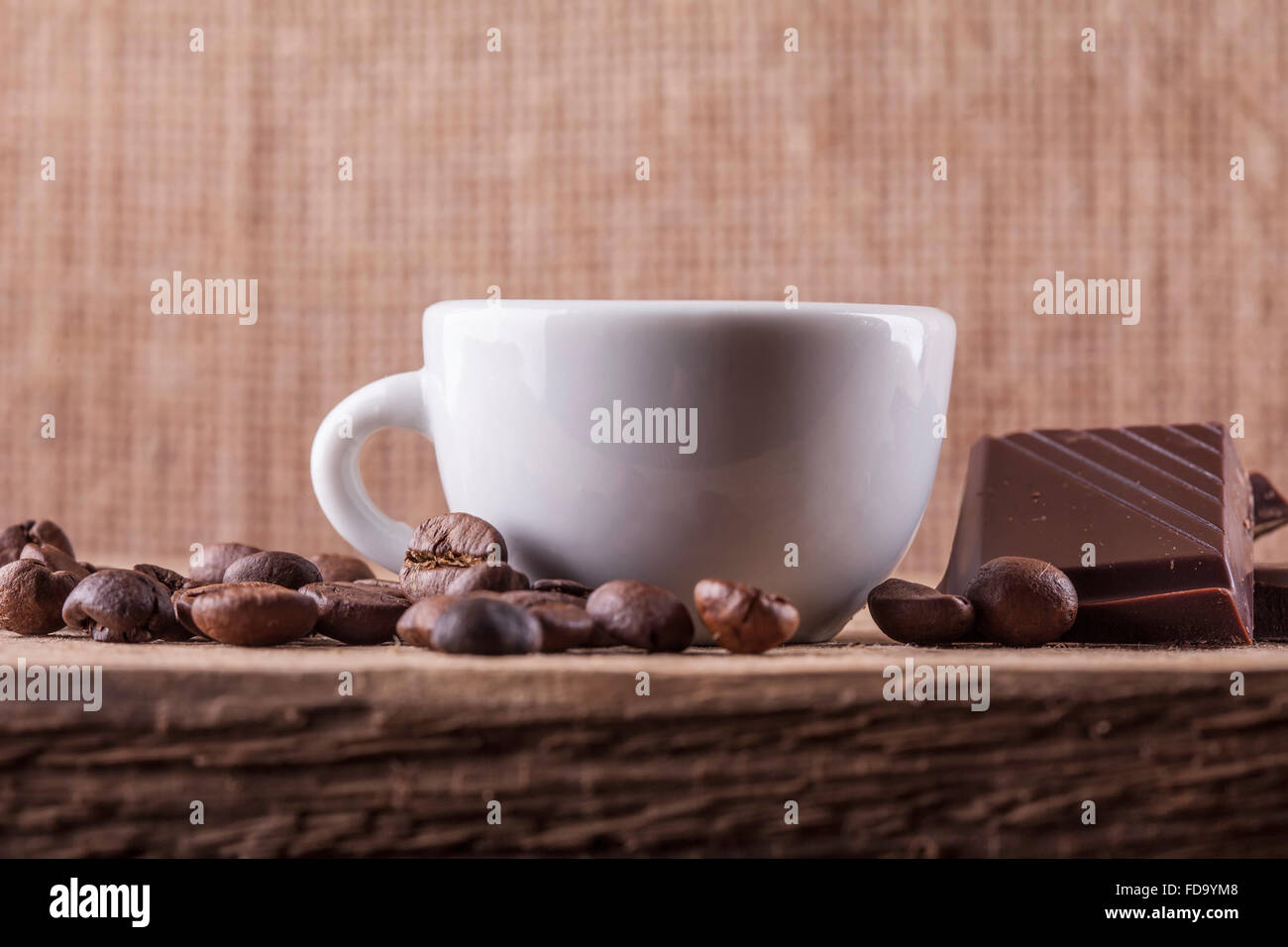 Tasse, Kaffee-Bohnen, Schokolade auf einem Holzbrett Closeup Hintergrund Stockfoto