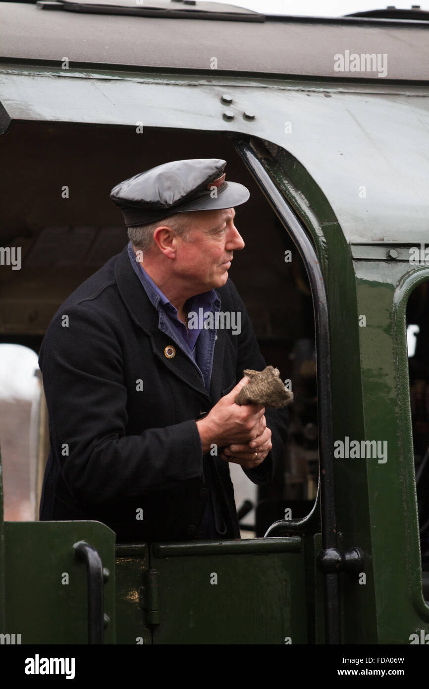 Ein Fahrer Uhren aus seinen Motor auf der Great Central Railway mit Tuch in der hand und traditionellen Fett top Cap. Stockfoto