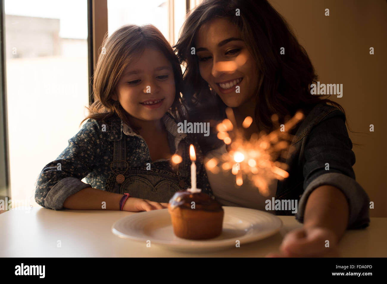 Mutter und Tochter feiert Geburtstag mit Cupcake und Wunderkerzen Stockfoto