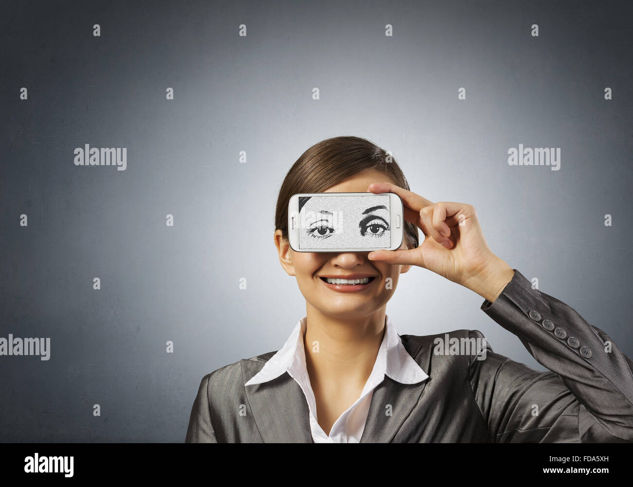 Schöne junge Frau mit Handy gegen ihre Augen Stockfoto