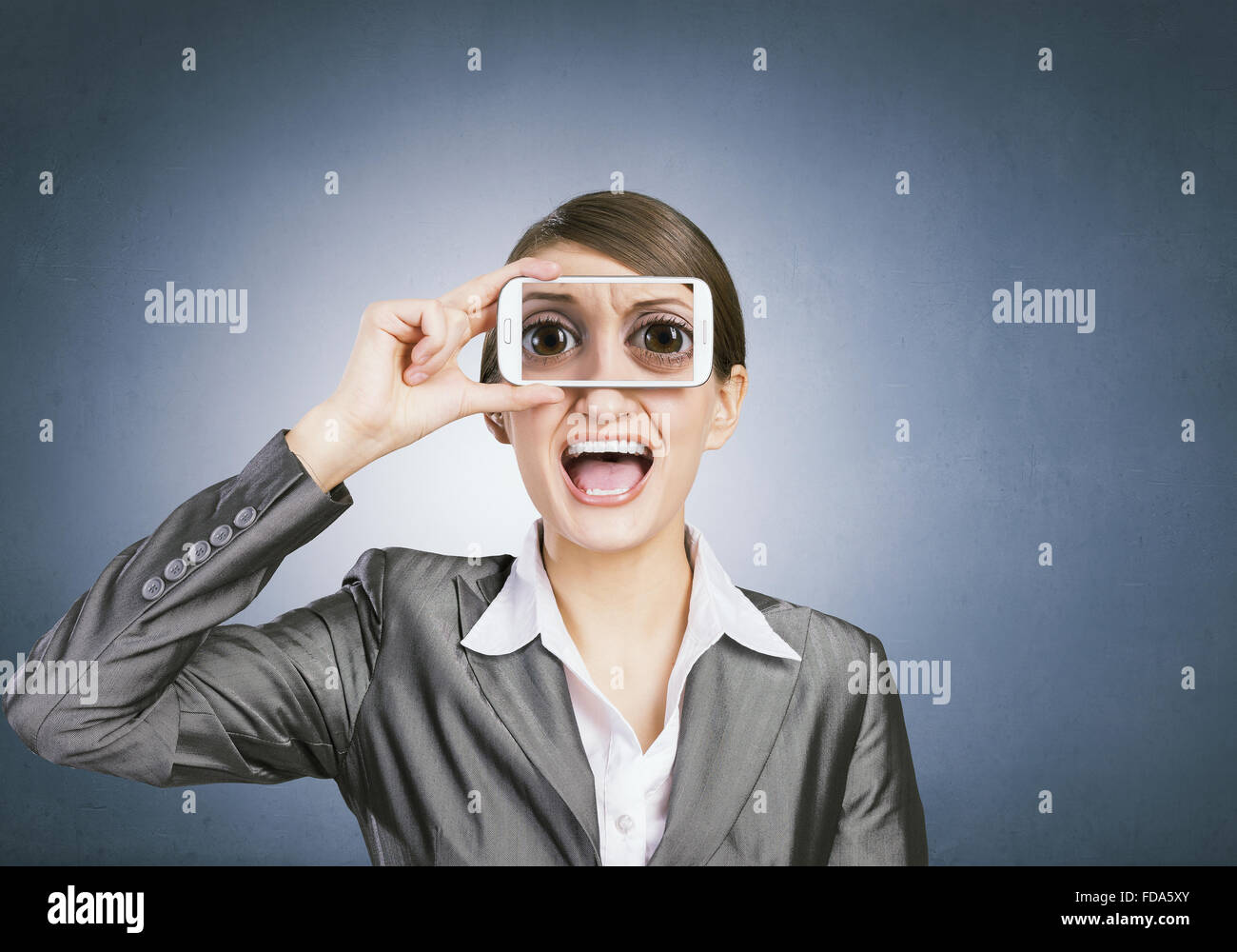 Schöne junge Frau mit Handy gegen ihre Augen Stockfoto