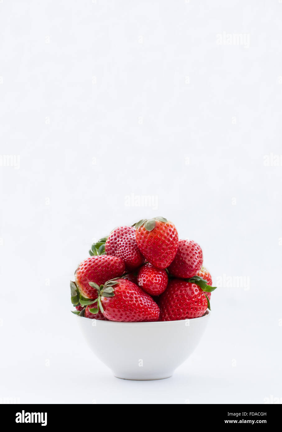 Eine Schüssel voll mit frischen Erdbeeren auf einem isolierten weißen Hintergrund. Hochformat. Stockfoto