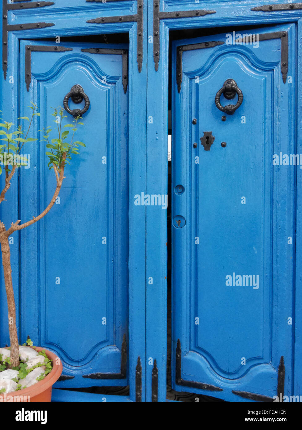 Paar dekorative blaue Türen mit zwei großen ringförmigen Klopfern und schwarzen Metallwinkeln, Frigiliana, Malaga, Andalusien, Spanien. Stockfoto