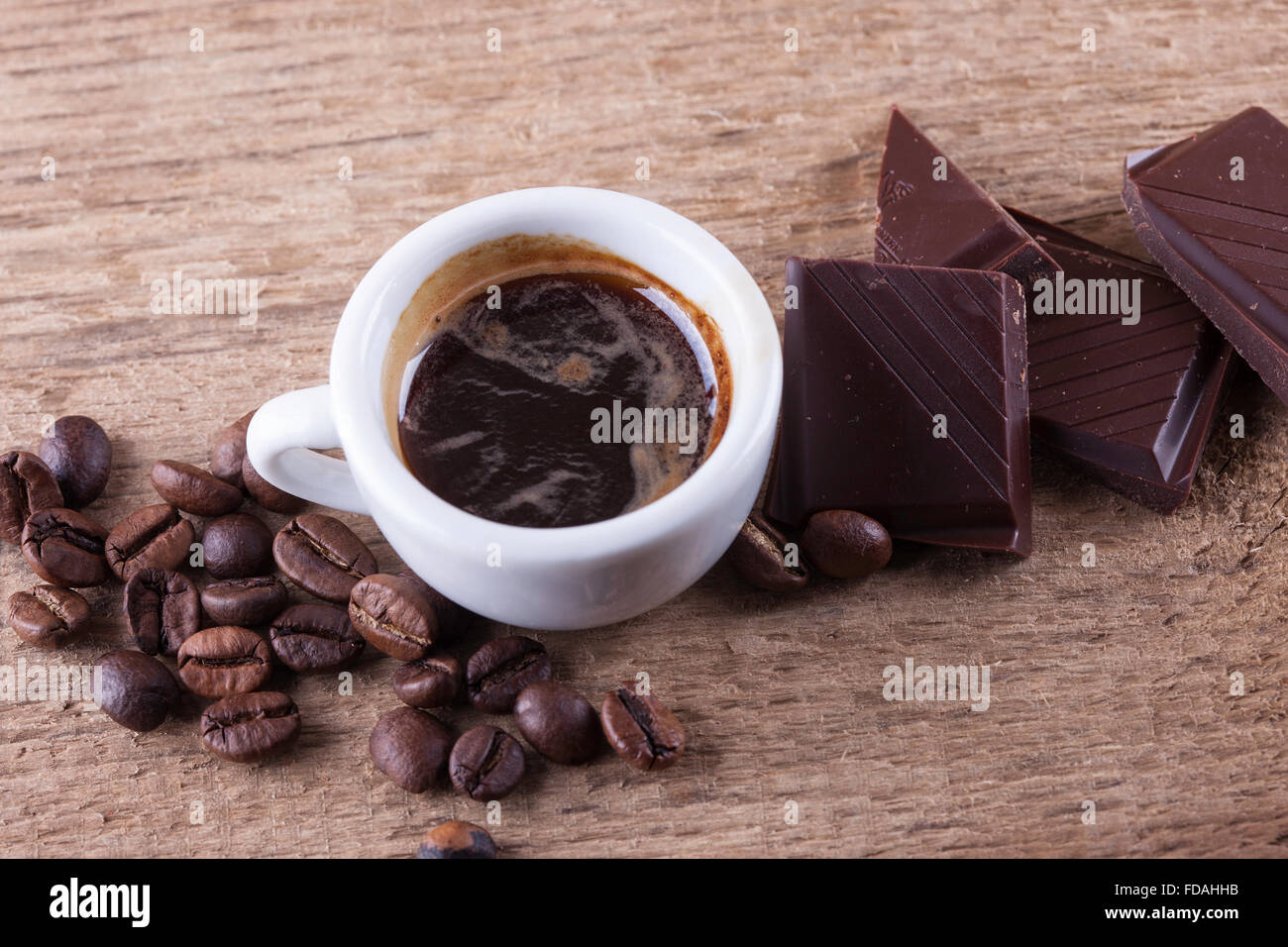 Tasse, Kaffeebohnen, Schokolade, Holzbrett Closeup Draufsicht Hintergrund Stockfoto