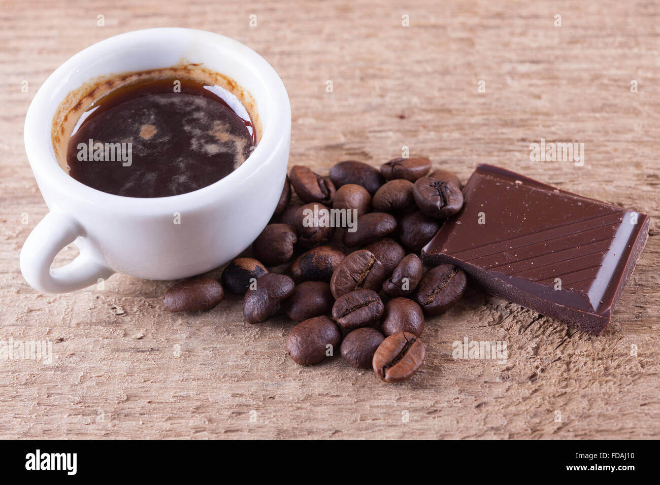 Tasse, Kaffeebohnen, Schokolade, Holzbrett Closeup Draufsicht Hintergrund Stockfoto