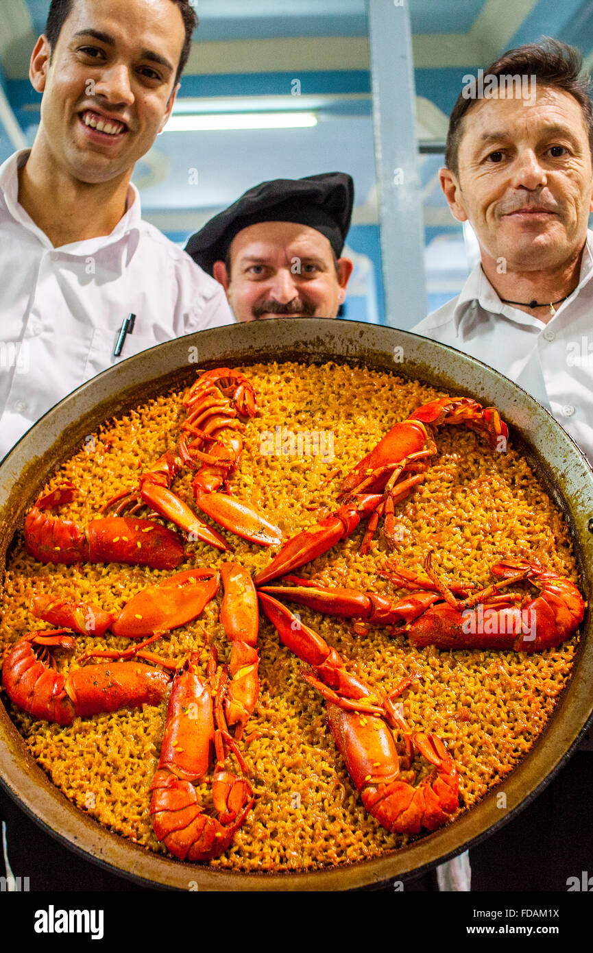 Kellner zeigen eine Paella. In La Pepica Restaurant, 6 Passeig Neptú Malvarrosa Strand. Valencia
